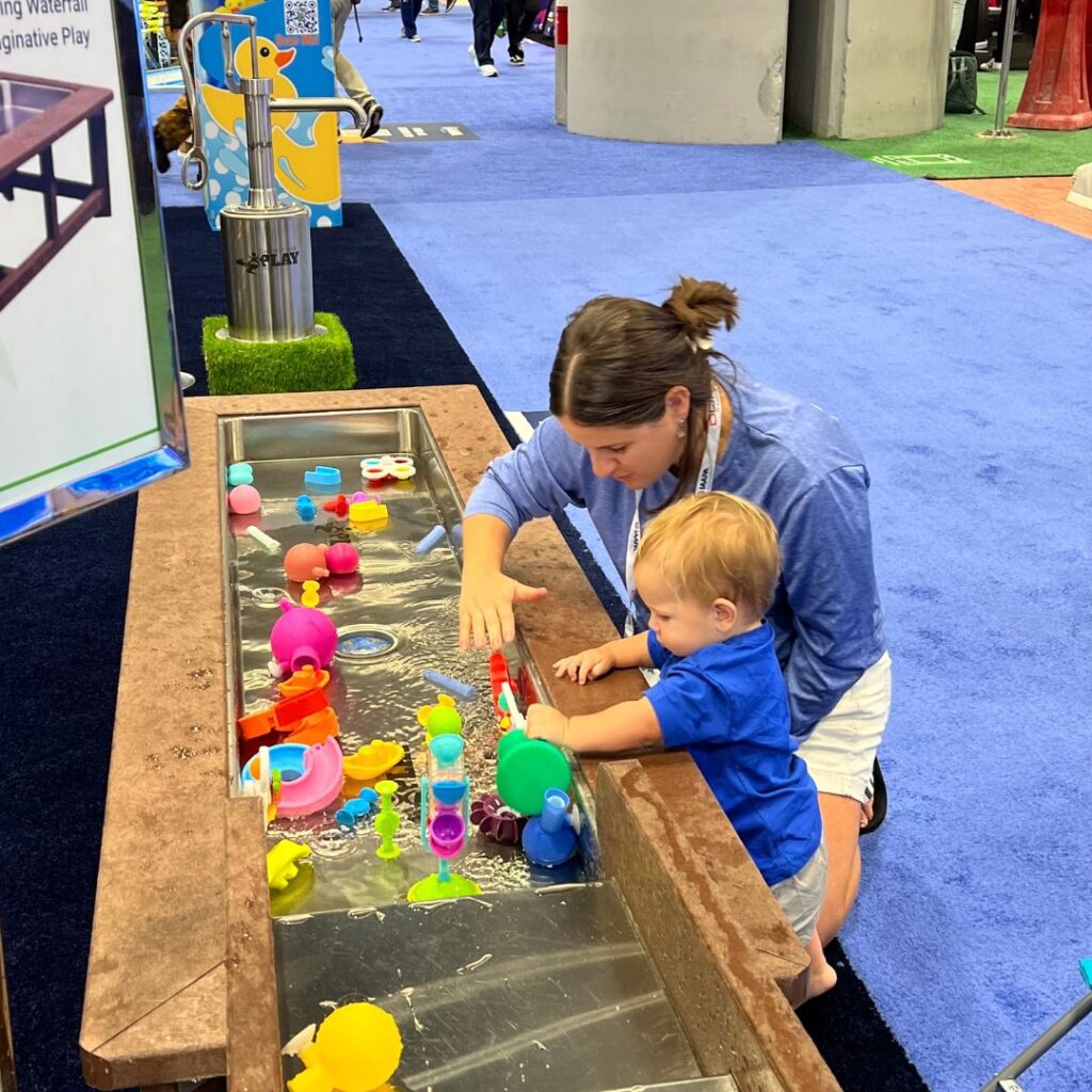a child playing with brightly colored toys in a Cadron Creek Play water trough.