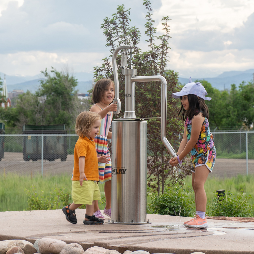 Pump-n-Play water feature installed at Spur Backyard in Denver, set within an outdoor children’s play space